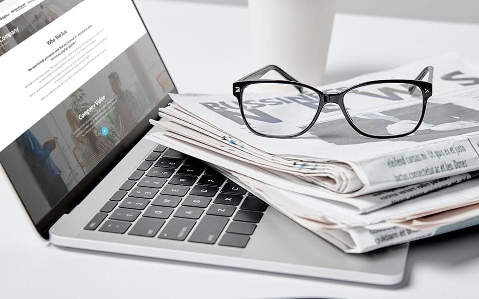 Laptop con la sección «quiénes somos» y unos lentes encima