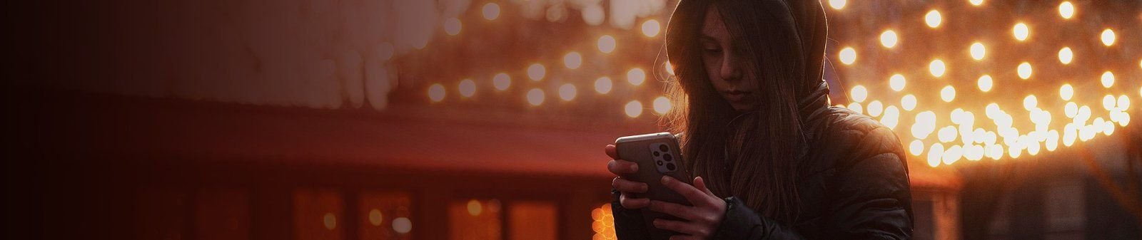 A person playing on their phone surrounded by lights